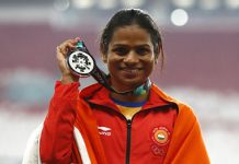India's Dutee Chand celebrates on the podium after winning the silver medal in the women's 100m final during the athletics competition at the 18th Asian Games in Jakarta, Indonesia, Sunday, Aug. 26, 2018. (AP Photo/Bernat Armangue)